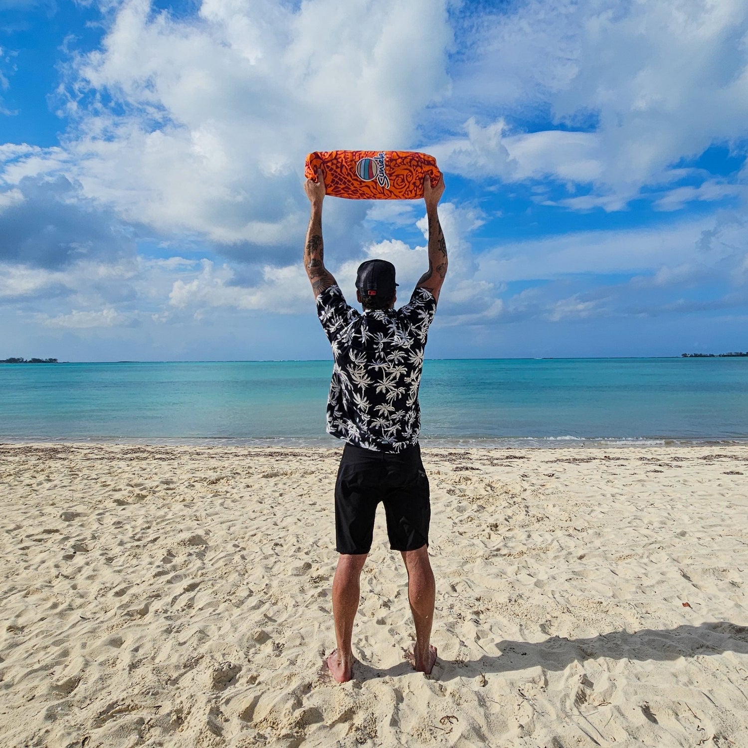 Man standing on the beach holding a packed Suniela beach cabana overhead, showing its compact and lightweight design