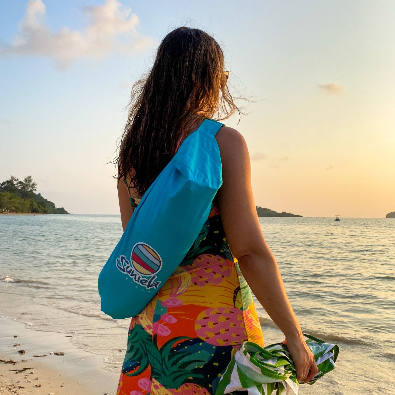 Woman carrying a Turquoise Suniela portable beach cabana in a compact carry bag