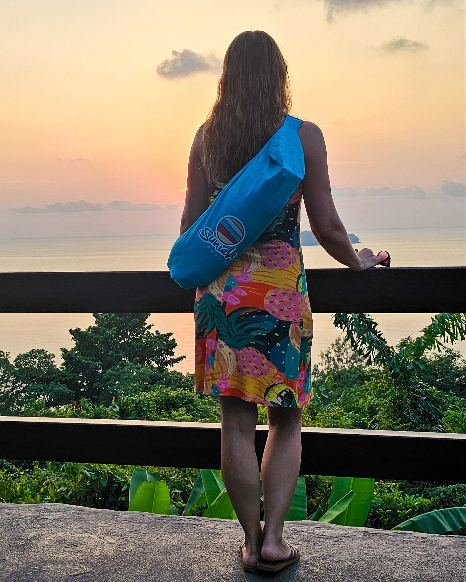 Woman overlooking the ocean carrying a Suniela portable beach cabana in a compact carry bag