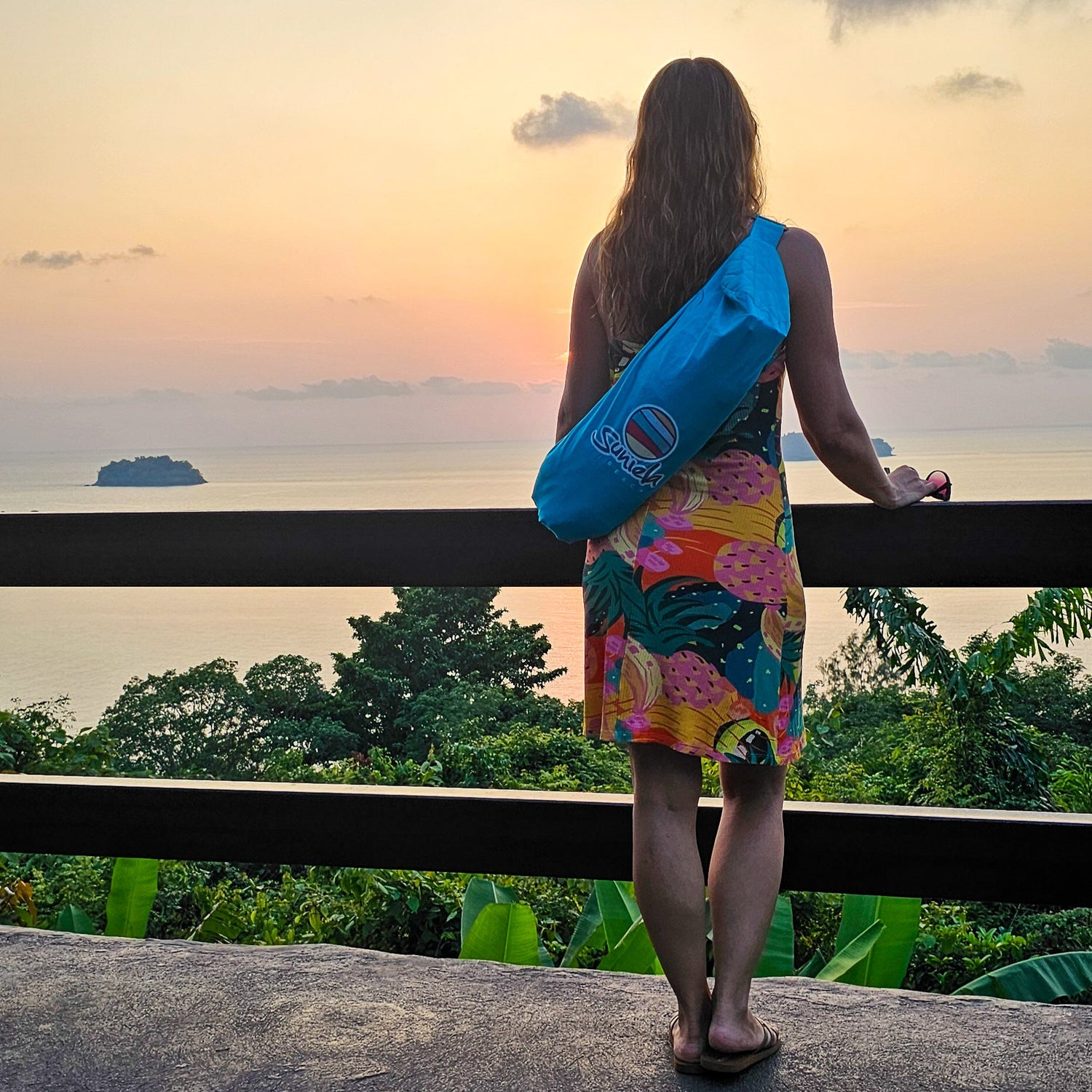 Woman overlooking the ocean carrying a Suniela portable beach cabana in a compact carry bag