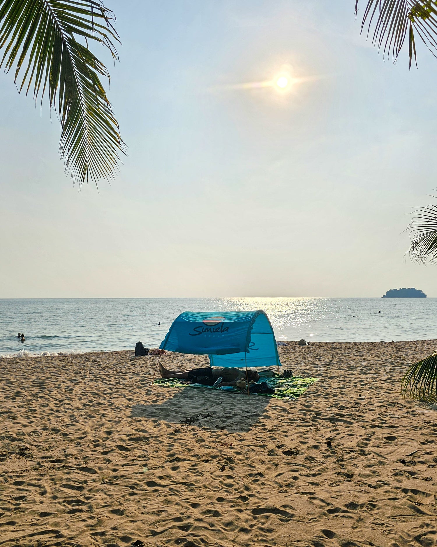 Turquoise Suniela portable beach cabana set up on a sandy beach by the ocean