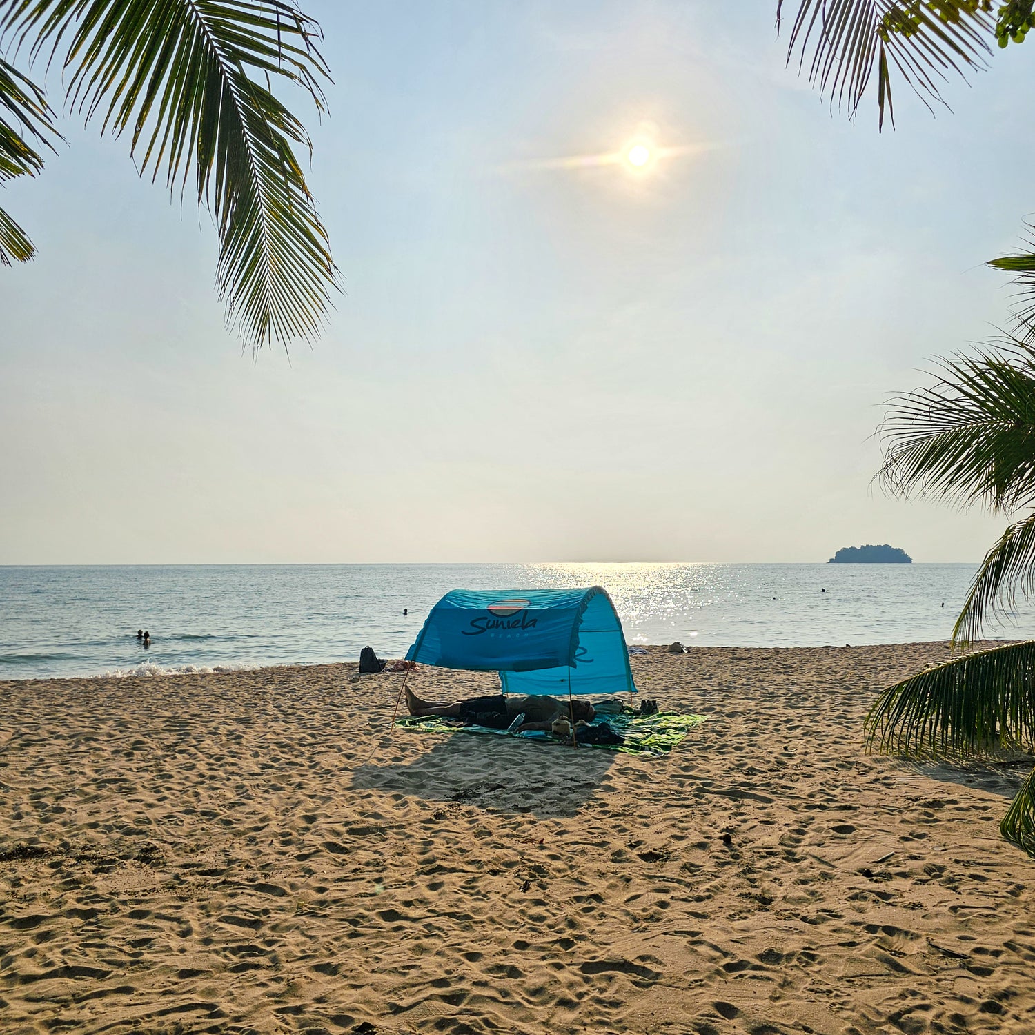 Turquoise Suniela portable beach cabana set up on a sandy beach by the ocean