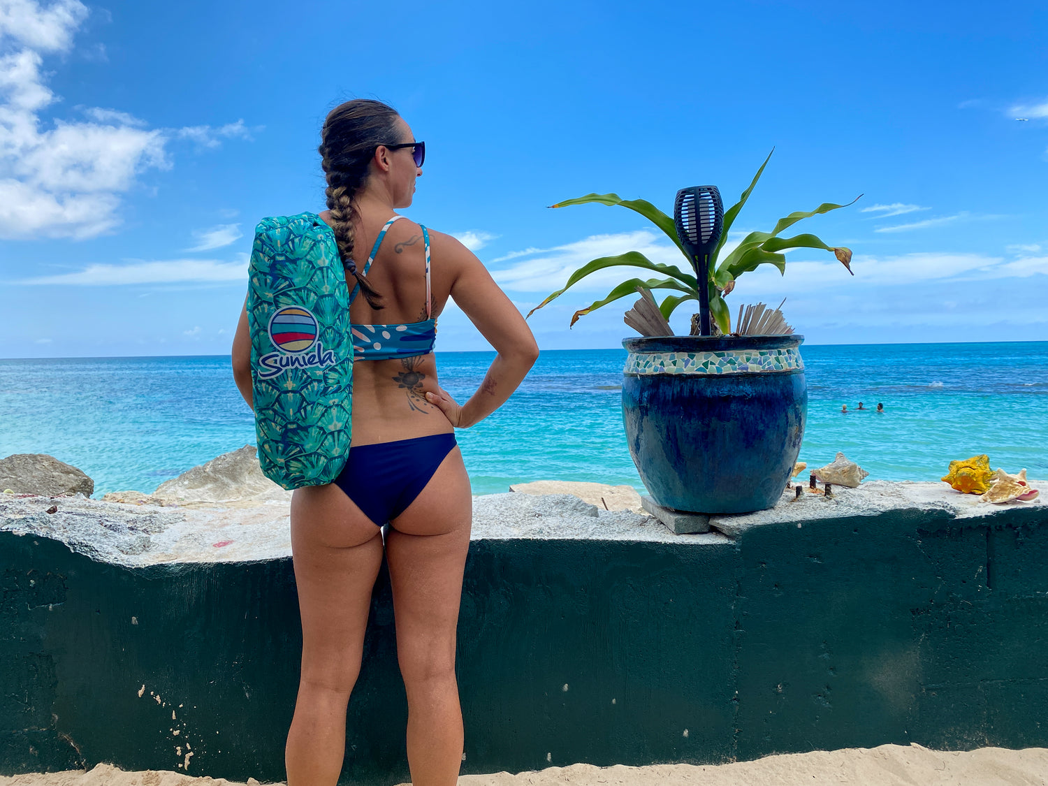 woman carries Suniela Beach shade cabana on her back while looking out at the Caribbean sea