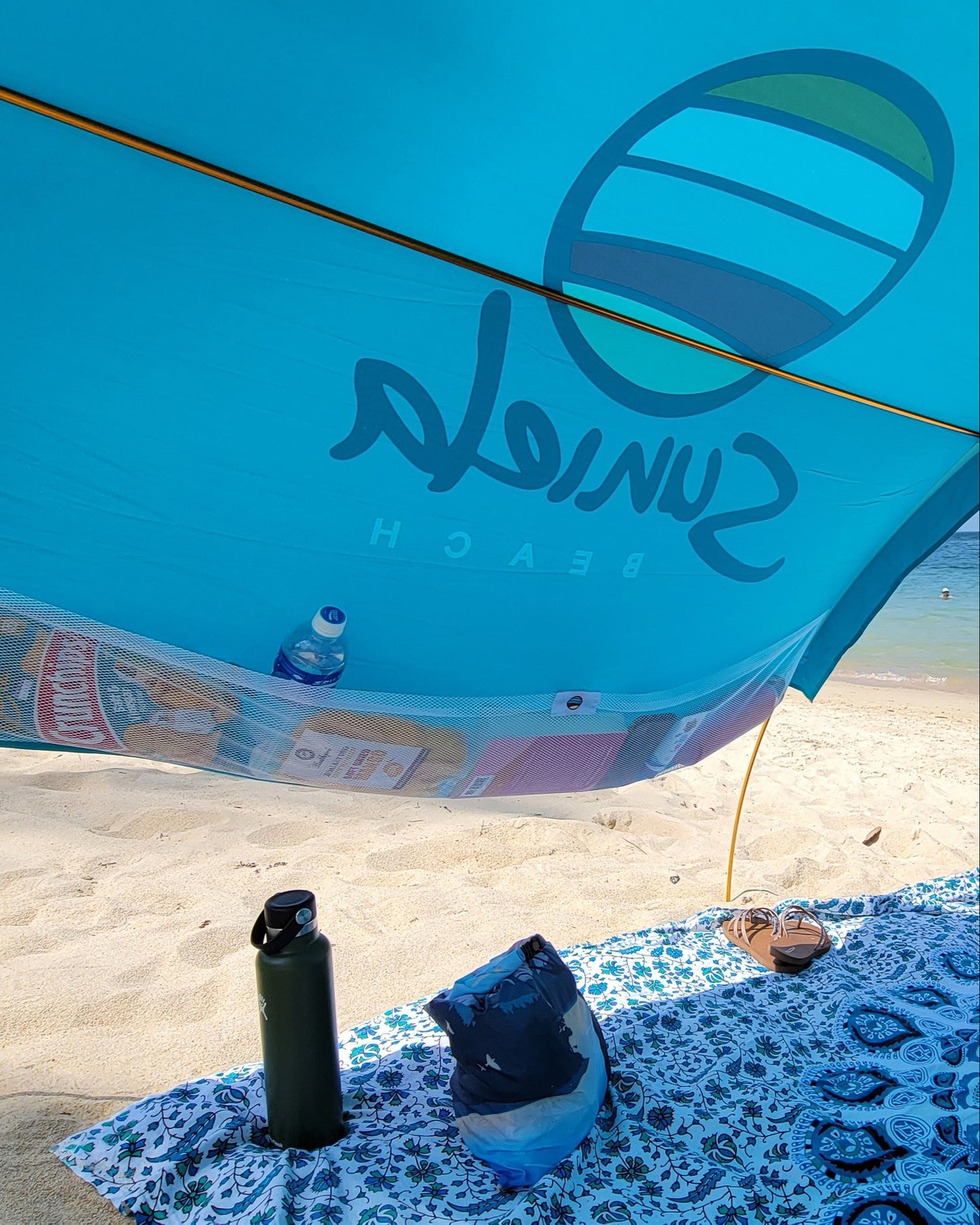 Turquoise cotton shade tent with large mesh pockets for beach essentials