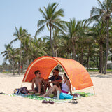 Friends relaxing under a Suniela beach cabana with the Tribal Jungle orange cotton canopy and fringe on a palm-lined beach