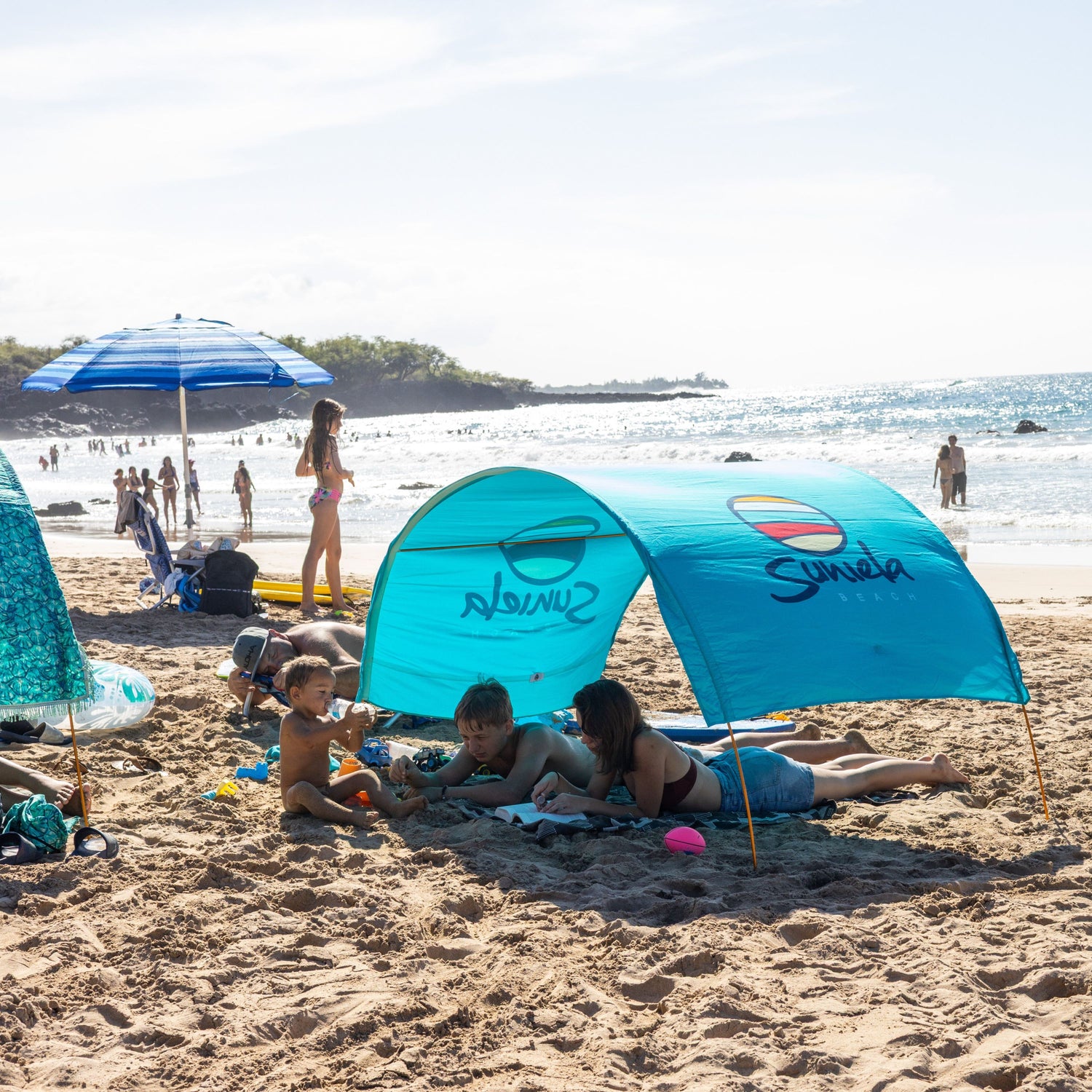 Family at the beach with a blue Suniela shade tent_printTurquoiseSuniela