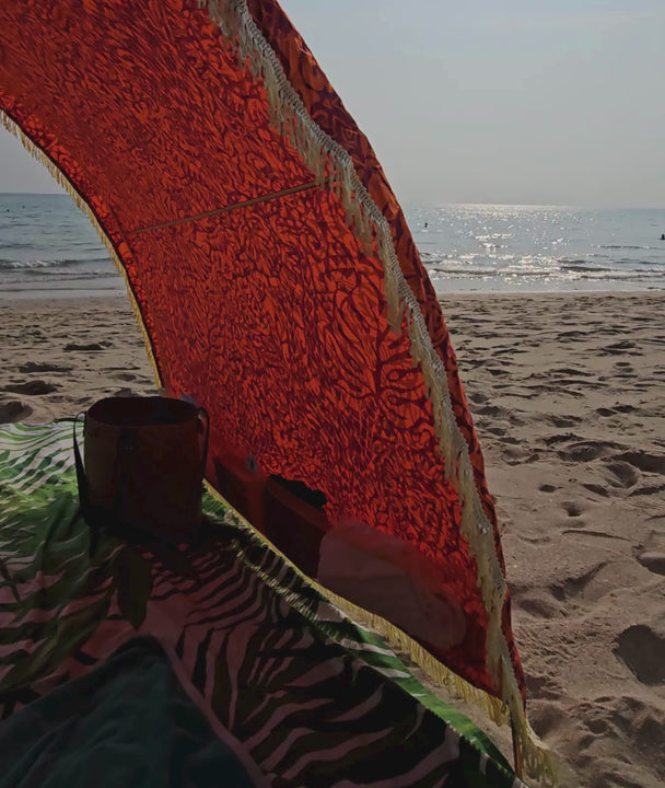 video showing details like pockets full of accessories , fringes and tribal jungle  pattern on a Suniela shade cabana on a sandy beach