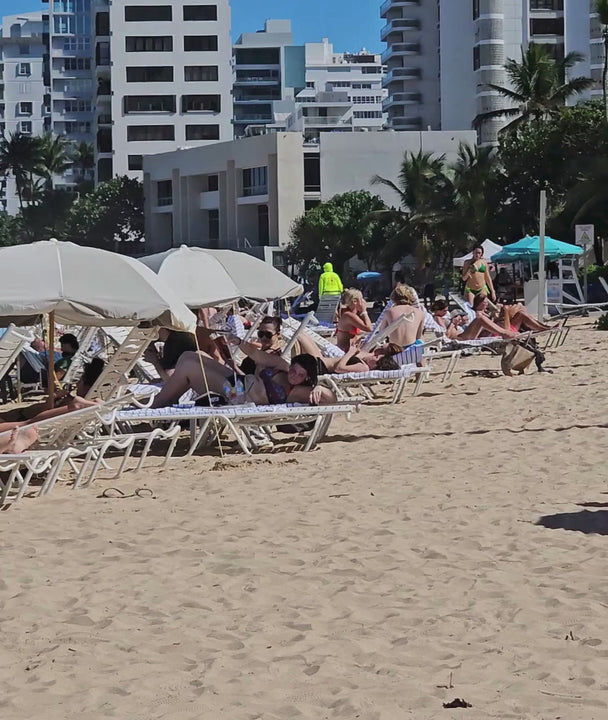 panoramic video of a crowded beach with loungers and parasols everywhere, and a lone Suniela shade in turquoise colour standing out from the rest. 