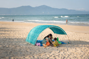 family plays in the shade of their Suniela Beach portable cabana